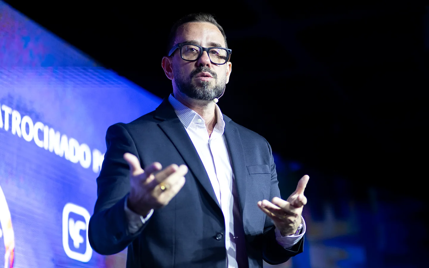 Dr. Diogo Viana no palco, gesticulando durante a condução de uma discussão clínica ao vivo